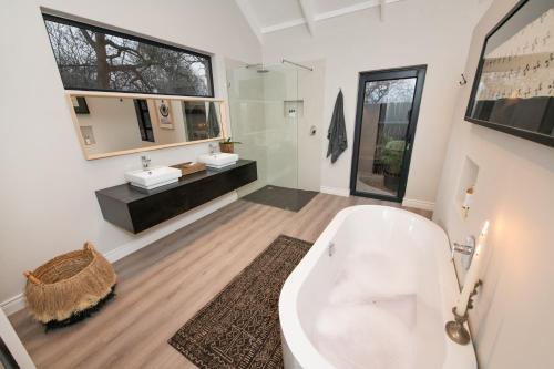 a bathroom with a tub and a sink and a mirror at Moya Safari Villa in Hoedspruit