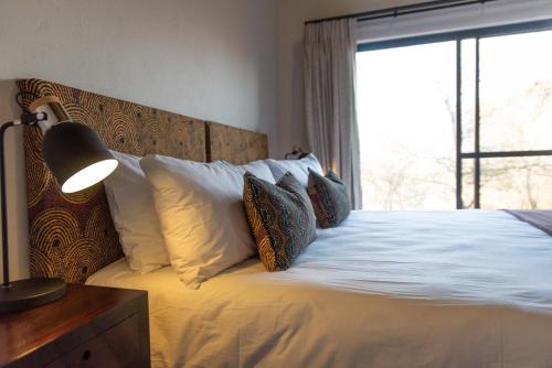a bedroom with a bed with white sheets and a window at Moya Safari Villa in Hoedspruit