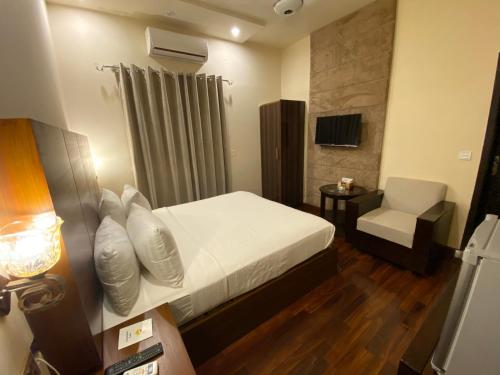 a hotel room with a bed and a chair at Shelton’s Rezidor Lahore in Lahore