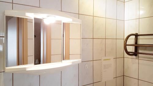 a bathroom with a mirror and a light on a wall at Monis gemütliche Ferienwohnungen in Suhl