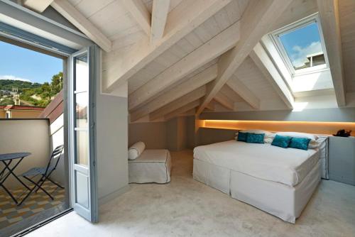 a bedroom in a loft with a bed and windows at Boutique Hotel de la Ville in Laigueglia