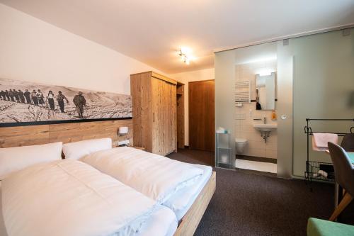 1 Schlafzimmer mit einem großen weißen Bett und einem Badezimmer in der Unterkunft Haus Gamberg in Sankt Anton am Arlberg