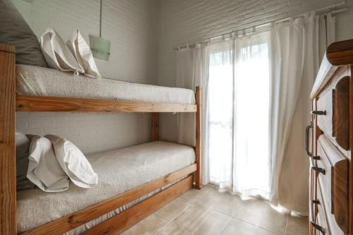 a bedroom with two bunk beds and a window at Valeria House Rental Suites in Valeria del Mar