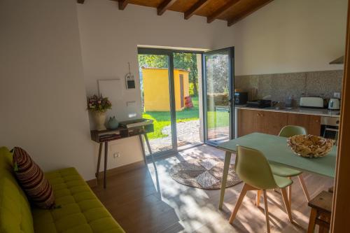 a living room with a green table and a kitchen at Casas do Prazo - Turismo Rural in Nogueira