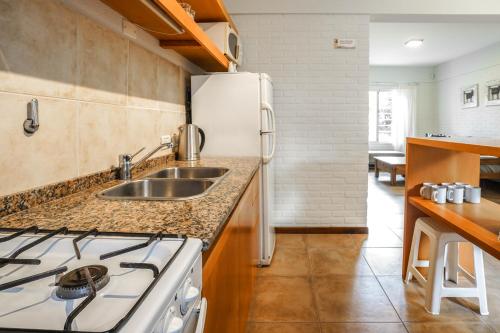 a kitchen with a stove and a sink and a refrigerator at Valeria House Rental Suites in Valeria del Mar