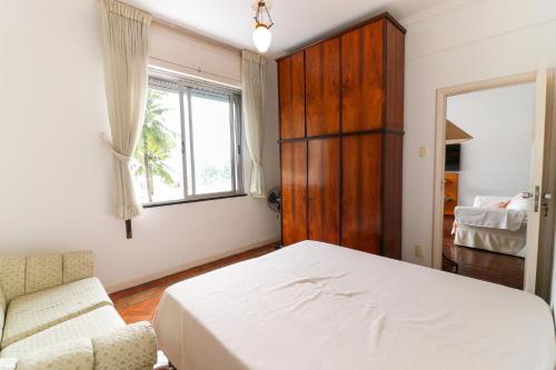 a bedroom with a bed and a chair and a window at VISTA MAR / AVENIDA ATLÂNTICA / COPACABANA in Rio de Janeiro