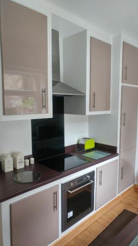 a kitchen with white cabinets and a black counter top at The Comfy House in Huddersfield