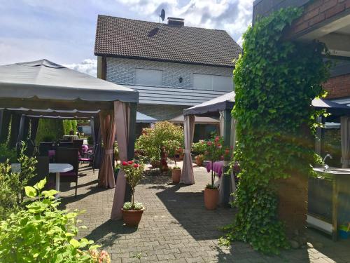 a patio with a bunch of potted plants and a building at Landgasthof Rheda Hotel - Restaurant in Rheda-Wiedenbrück