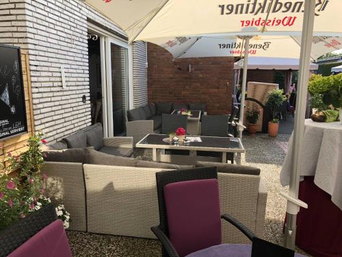a patio with couches and tables and an umbrella at Landgasthof Rheda Hotel - Restaurant in Rheda-Wiedenbrück