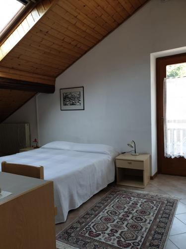 a bedroom with a bed and a table and a window at ANESI appartamenti in Baselga di Pinè