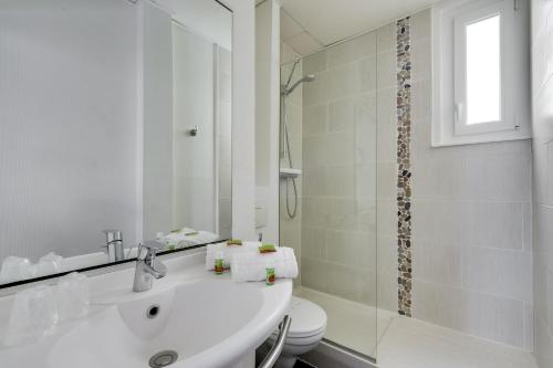 a white bathroom with a sink and a shower at Hotel Chagnot in Lille