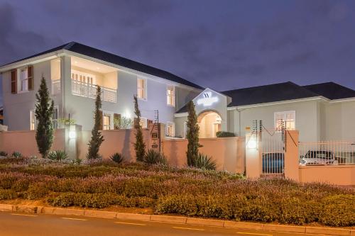 a large white house with a fence at Waterstone Lodge in Somerset West