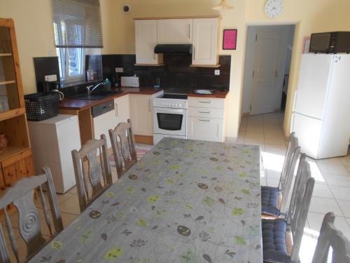 a kitchen with a table and chairs and a kitchen with white appliances at Gîte de la Cuve in Huisnes-sur-Mer