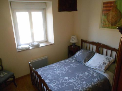 a bedroom with a bed with a blue comforter and a window at Gîte de la Cuve in Huisnes-sur-Mer