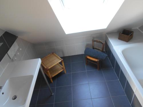 een badkamer met een wastafel, een bad en een stoel bij Gîte de la Cuve in Huisnes-sur-Mer