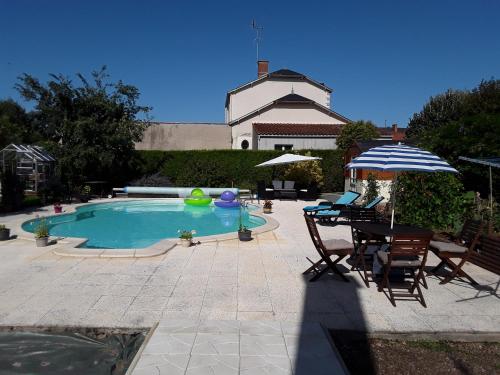 une piscine avec une table, des chaises et un parasol dans l'établissement Maison Vuyk, à Nalliers