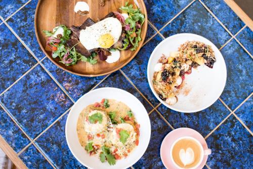 a table with plates of food and a bowl of salad at East Austin Hotel in Austin