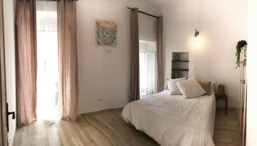 a bedroom with a white bed and a large window at Cal Morrudet in L'Ametlla de Mar