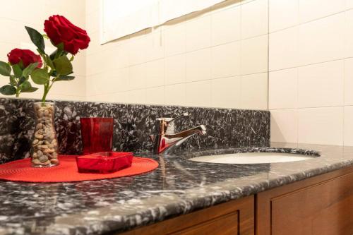 a bathroom counter with a sink and a vase of roses at Italianway - Polese 36 B in Bologna