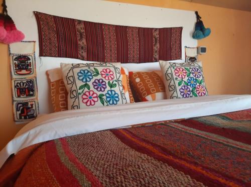 a bed with a bunch of pillows on it at Quechua lodge Titicaca in Puno