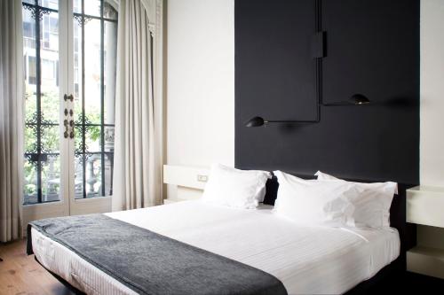 a bedroom with a bed with white sheets and a window at Praktik Rambla in Barcelona