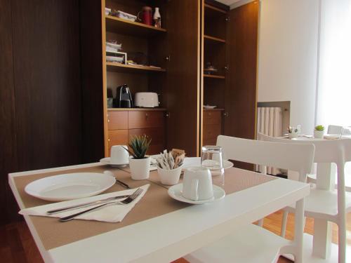 a white dining room table with white plates and utensils at Room 56 - Le Dimore in Bari