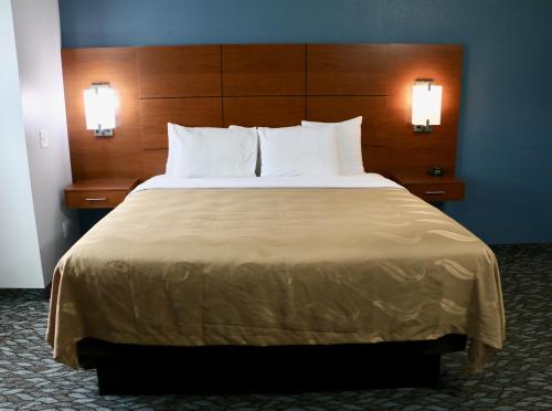 ein großes Bett in einem Hotelzimmer mit zwei Lampen in der Unterkunft Quality Inn & Suites Watertown Fort Drum in Calcium