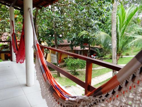 a hammock on a porch with a view of a garden at Pousada Cavalo Marinho in Pipa