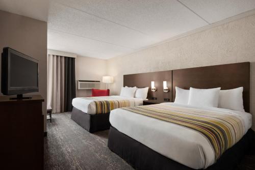 a hotel room with two beds and a flat screen tv at Country Inn & Suites by Radisson, Mt Pleasant-Racine West, WI in Sturtevant