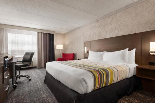 Habitación de hotel con cama grande y escritorio. en Country Inn & Suites by Radisson, Mt Pleasant-Racine West, WI en Sturtevant