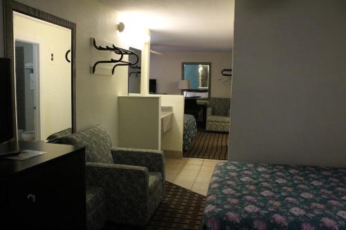 a hotel room with a bed and a chair and a mirror at American Inn Port O'Connor in Port O'Connor