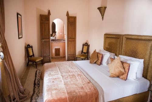 a bedroom with a large bed with two chairs at Riad Zamzam in Marrakesh