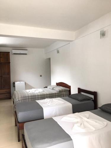 a room with three beds in a room at Pousada Recanto do Teimoso in Ubatuba