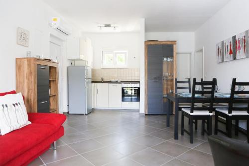 a living room with a red couch and a kitchen at Sea Breeze Gugic in Korčula