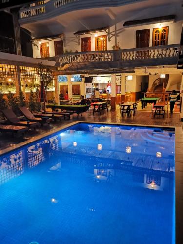 a large pool in a hotel with tables and chairs at Poolside Villa in Phnom Penh