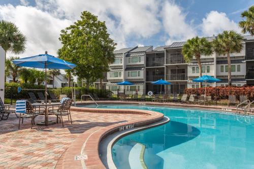 a pool at a hotel with tables and chairs and blue umbrellas at Orbit One Vacation Villas in Orlando