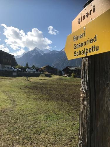 a yellow sign on a wooden pole with mountains in the background at Ferienwohnung Edelweiss in Grächen