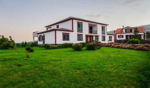 a large white house with a green yard at Moradia da Graça Guesthouse in Praia da Vitória