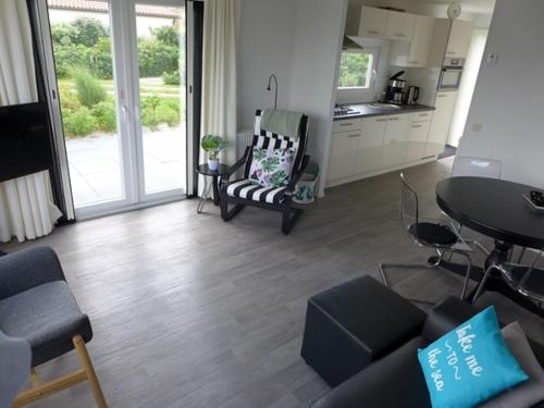 a living room with a table and chairs and a kitchen at Chalet Helmgras in Beek