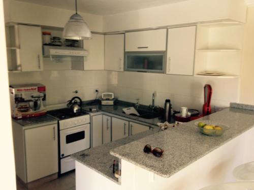 a kitchen with white cabinets and a granite counter top at Confortable departamento entero in Belén de Escobar