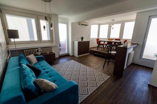 a living room with a blue couch and a table at Kristall Apartments 2 Panorama in Šabac