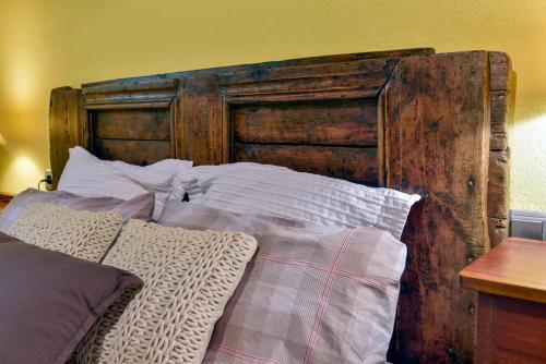 a bed with a wooden headboard and white pillows at Cal Gineró in Vall de Castellbò