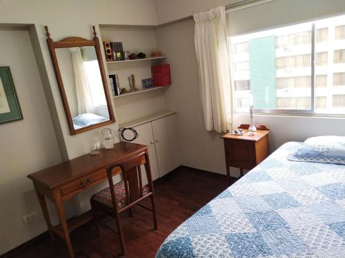 1 dormitorio con cama, escritorio y espejo en Susana´s Private Room with Breakfast - Miraflores, en Lima