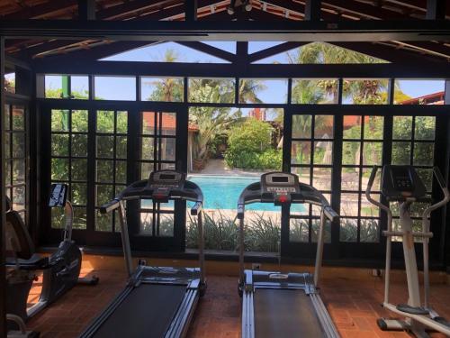 a gym with three treadmills in front of a pool at Hotel Pousada Ourinhos in Ourinhos