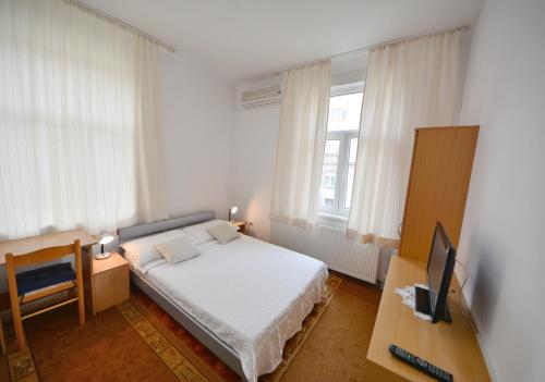 a small bedroom with a bed and a television at Guesthouse Sermageova in Zagreb