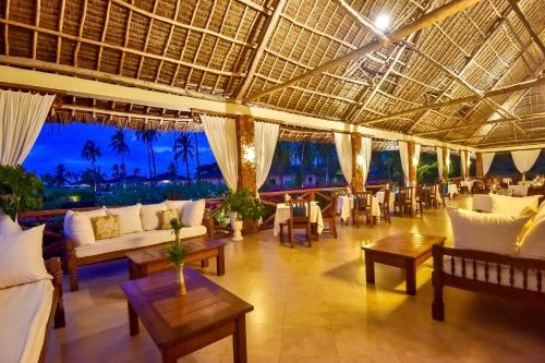 a restaurant with white couches and tables and chairs at The Sands Beach Resort in Bwejuu