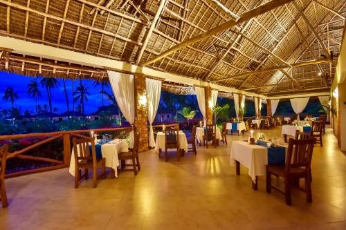 a dining room with tables and chairs in a resort at The Sands Beach Resort in Bwejuu