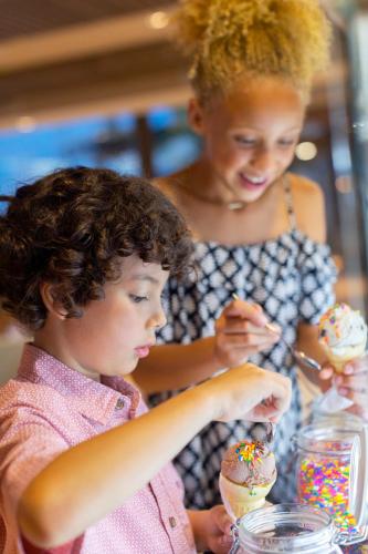 a woman and a child eating doughnuts at a table at Royalton Antigua, An Autograph Collection All-Inclusive Resort in Five Islands Village