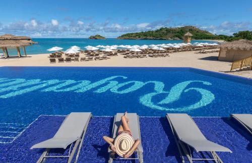 a woman laying on a beach chair next to a swimming pool at Royalton Antigua, An Autograph Collection All-Inclusive Resort in Five Islands Village