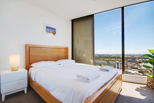 a bedroom with a large bed and large windows at Swainson at Vue in Adelaide